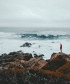 pensar a lo grande, thinking big, think big man standing on brown rock formation beside seashore during daytime