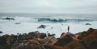 pensar a lo grande, thinking big, think big man standing on brown rock formation beside seashore during daytime