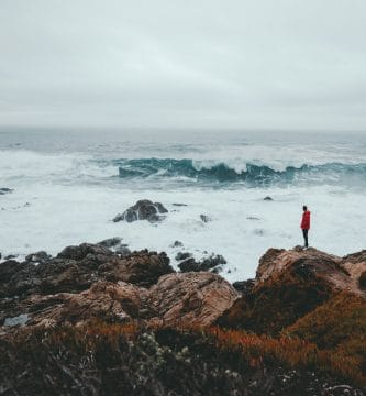 pensar a lo grande, thinking big, think big man standing on brown rock formation beside seashore during daytime