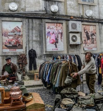 trade fairs clothes and bags displayed on road near building during daytime