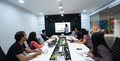 How B2B services can lower your costs 10 B2B services. people sitting at the table looking to another person standing in front of them